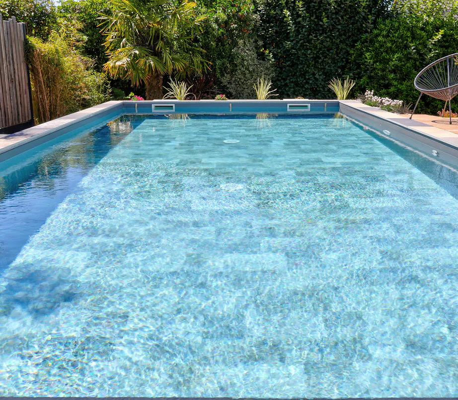 Piscine rectangulaire à eau cristalline entourée d’un jardin avec palmiers