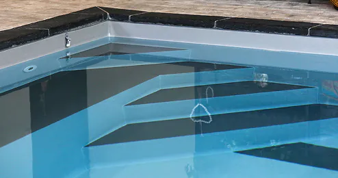 Marches d’angle immergées d’une piscine moderne avec margelles sombres