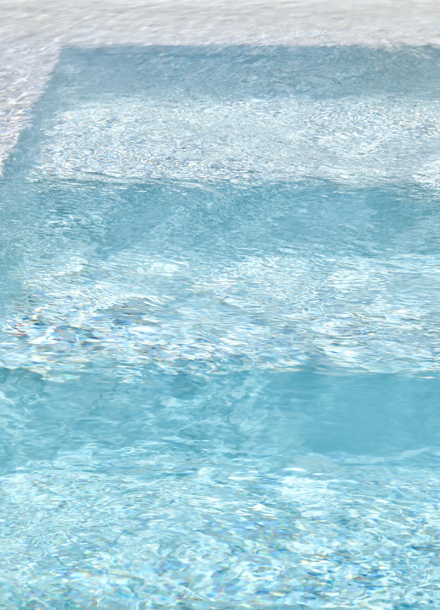 Vue plongeante sur des marches immergées dans une eau de piscine bleue
