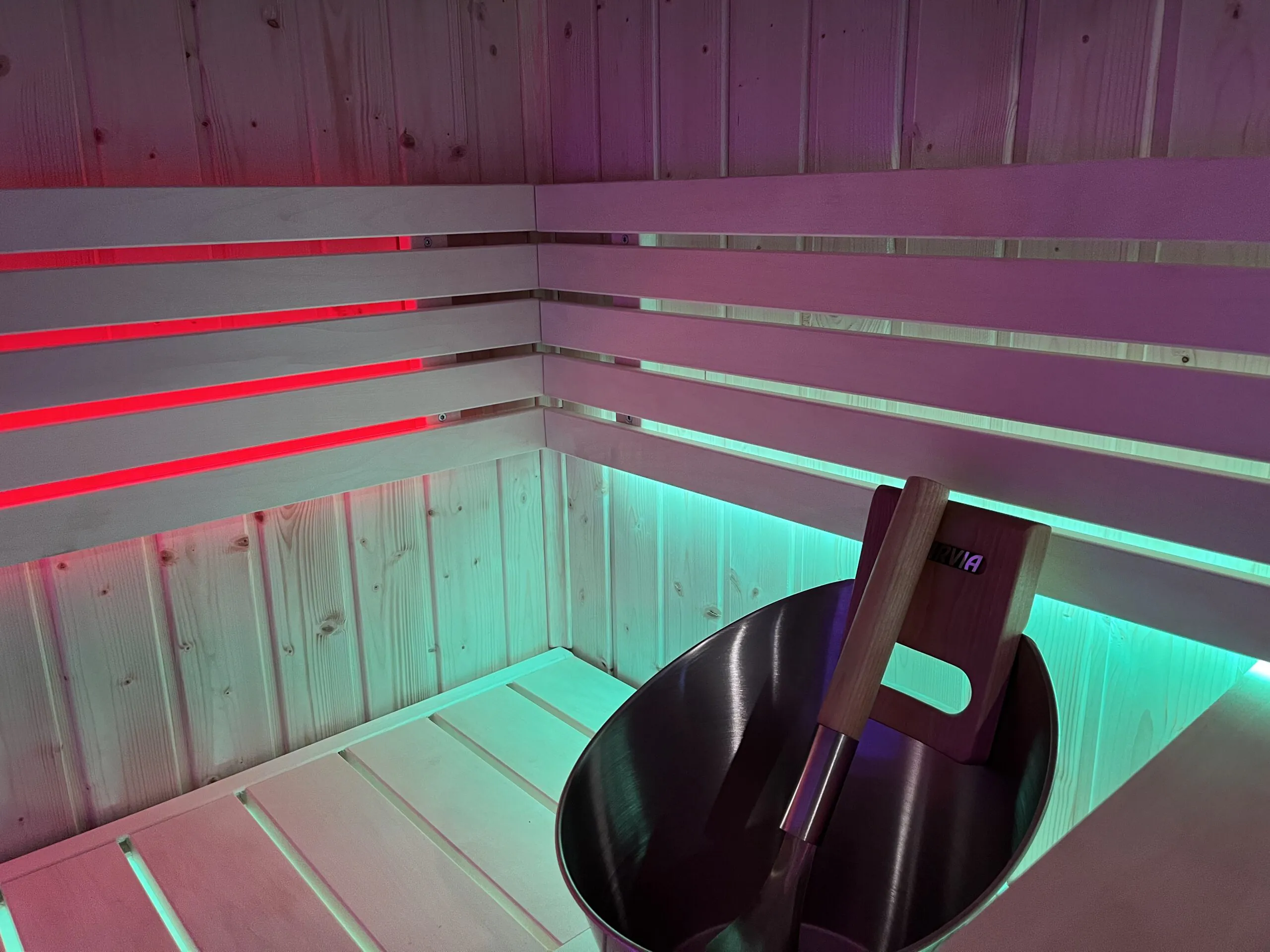 Intérieur de sauna infrarouge en bois avec éclairage LED rouge et turquoise